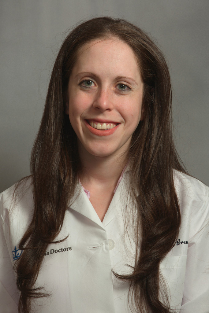 Woman in a white medical coat smiling at the camera.